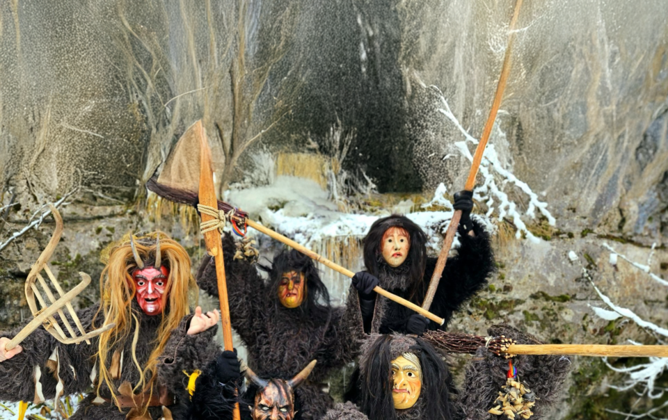 Gruppe traditioneller Perchten in Fellkostümen und Holzmasken im winterlichen Alpenraum, Darstellung des Perchtenlaufs.